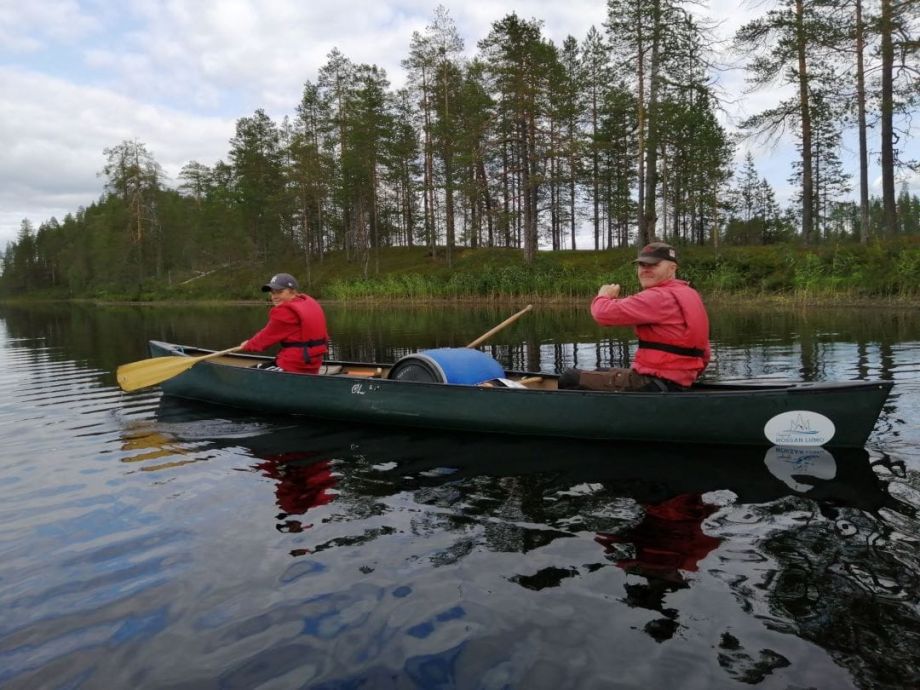 A father canoeieg with his son on an open Indian canoe.