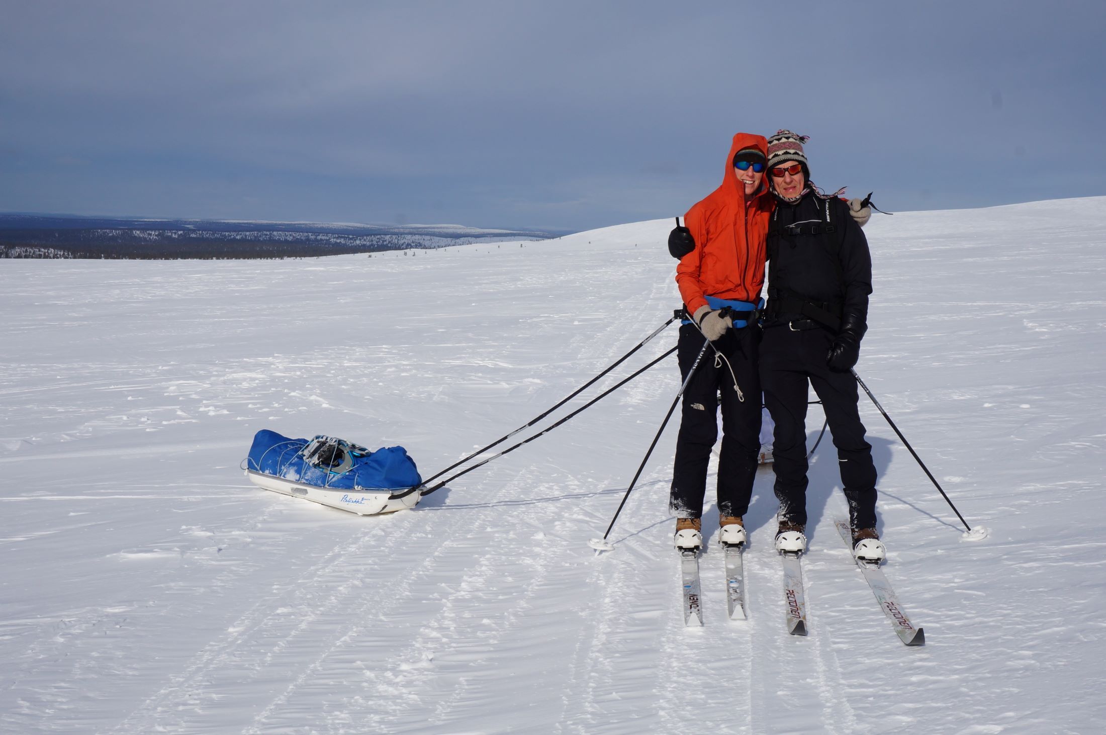 A couple on skis and with sledges on a fell.