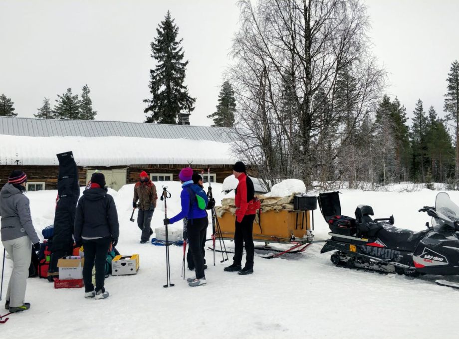 A group of skiers and a snowmobile getting ready for a new skiing day.