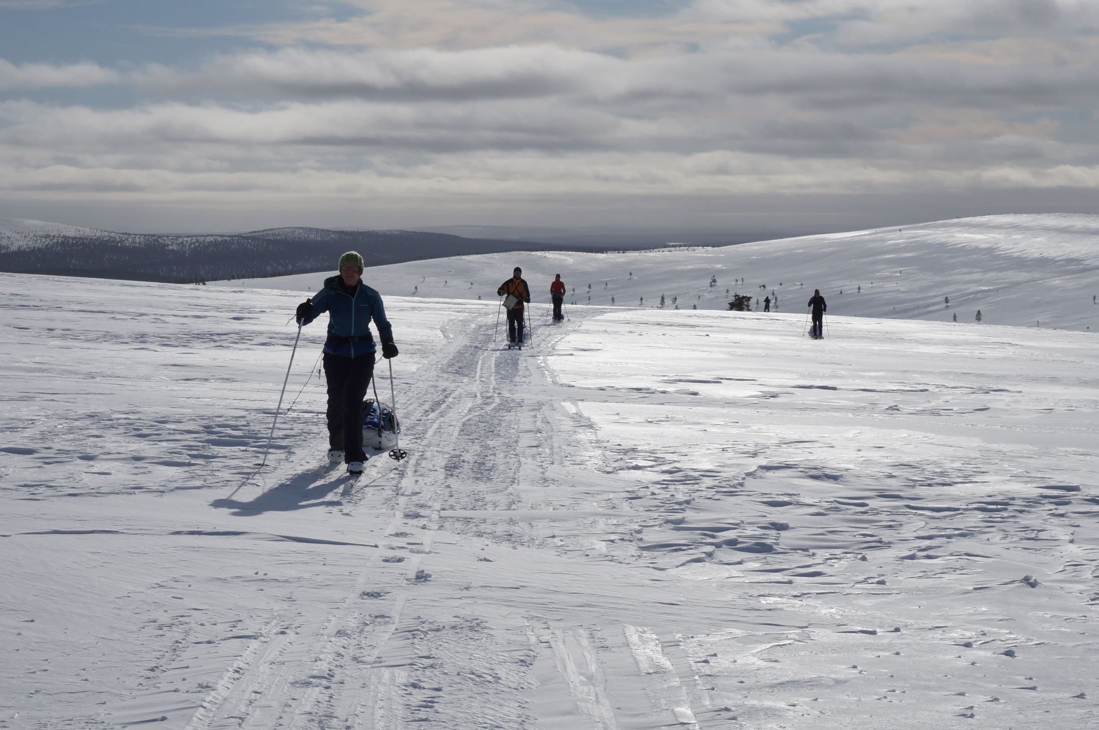 Skiers pulling sledges over a fell in Lapland.