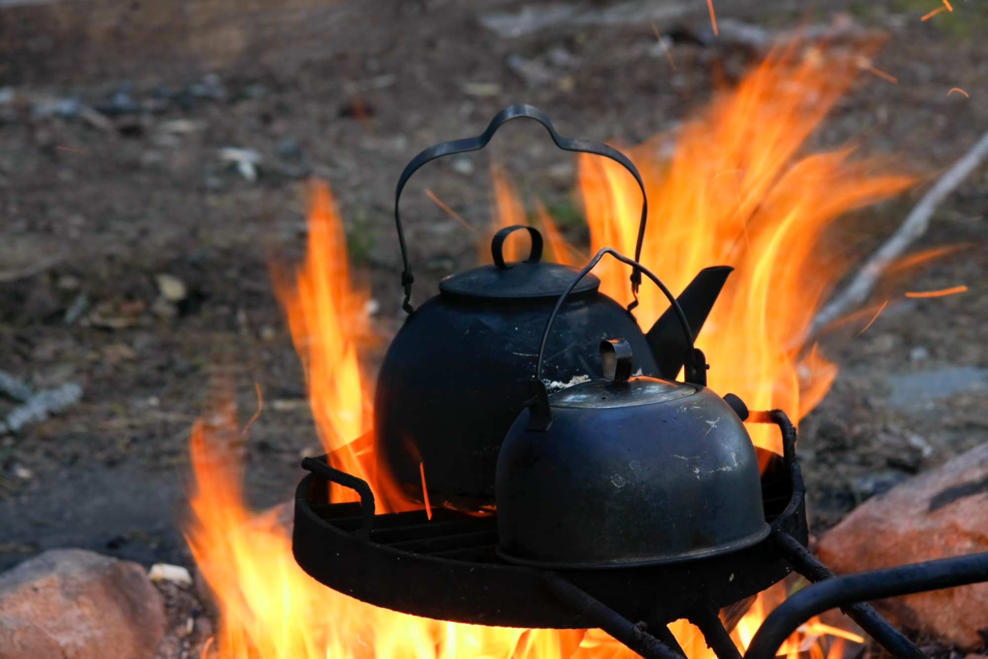 Two black coffee pots on an open fire.