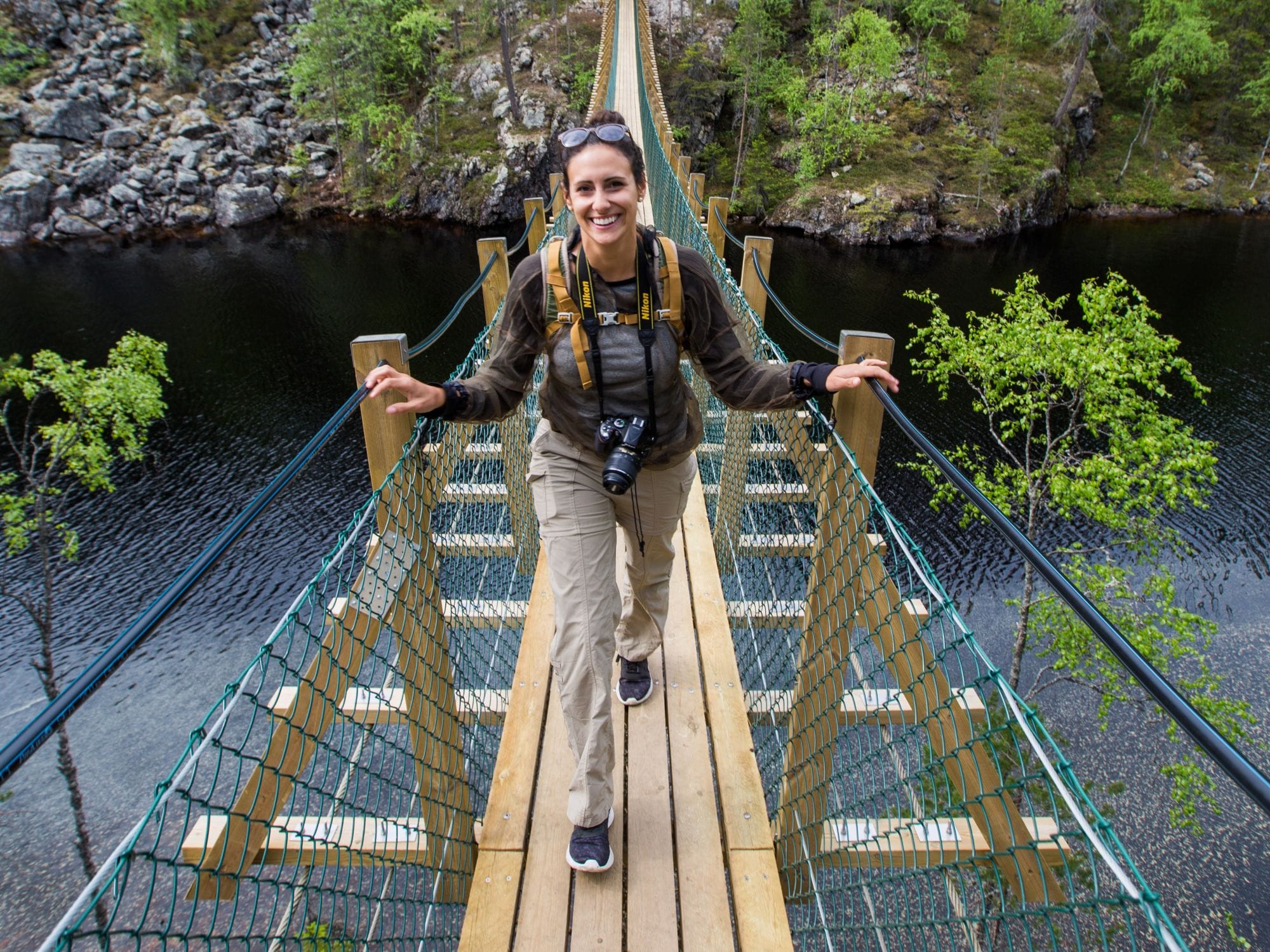 A girl on a suspension bridge crossing a lake