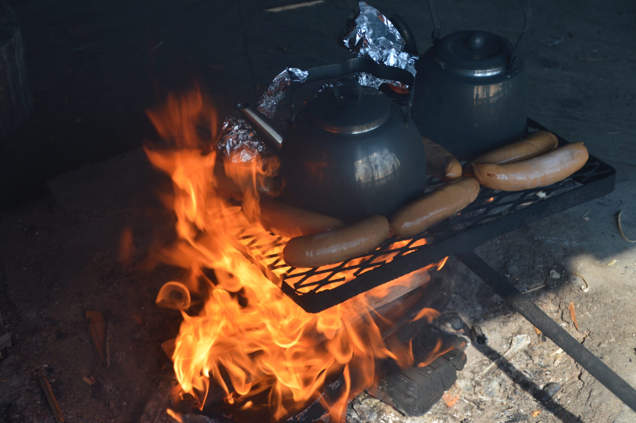 Tea pots and sausages over an open fire