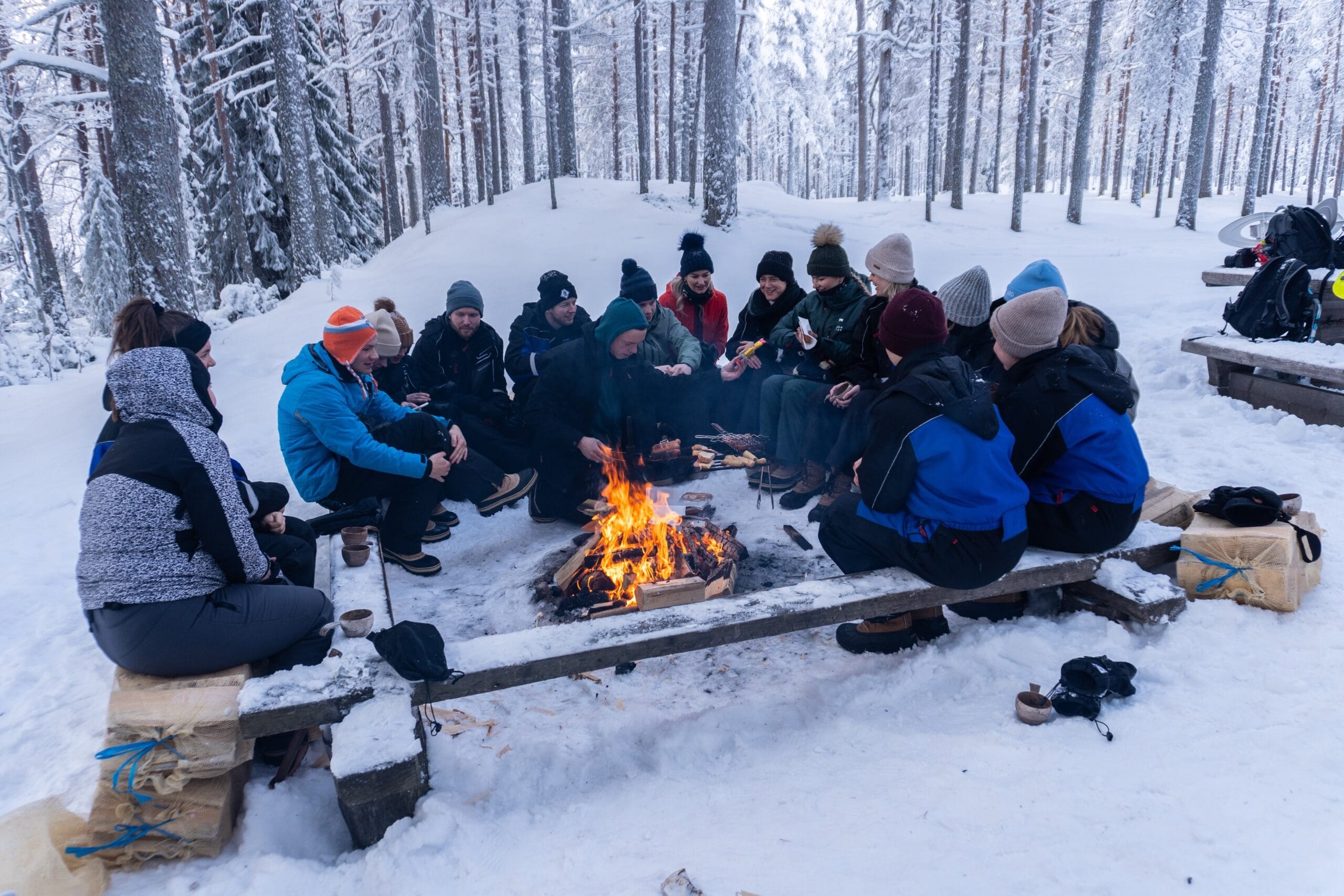 People having lunch around an open fire in winter.