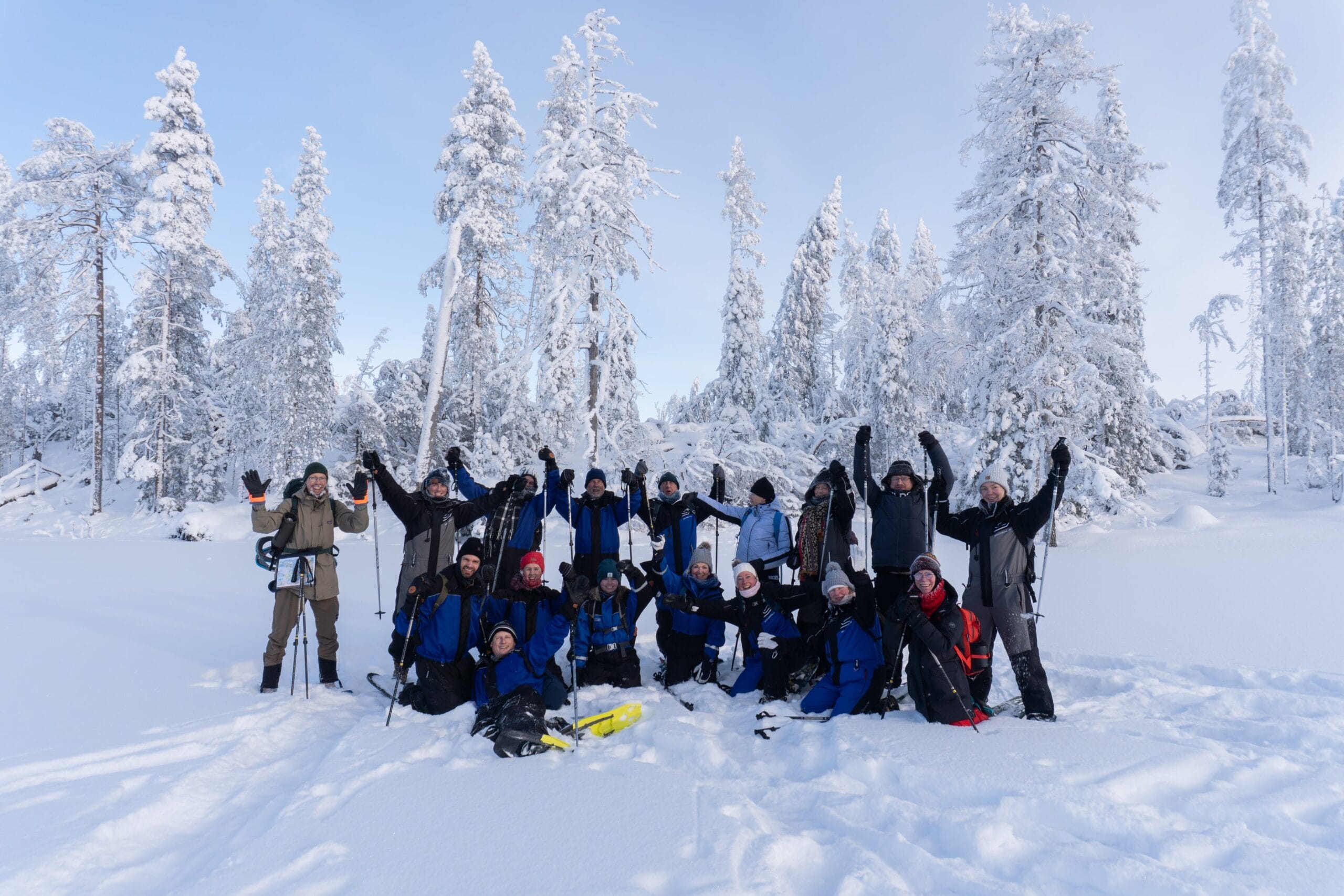 A group of people in the snowy scenery smiling and waving happily.
