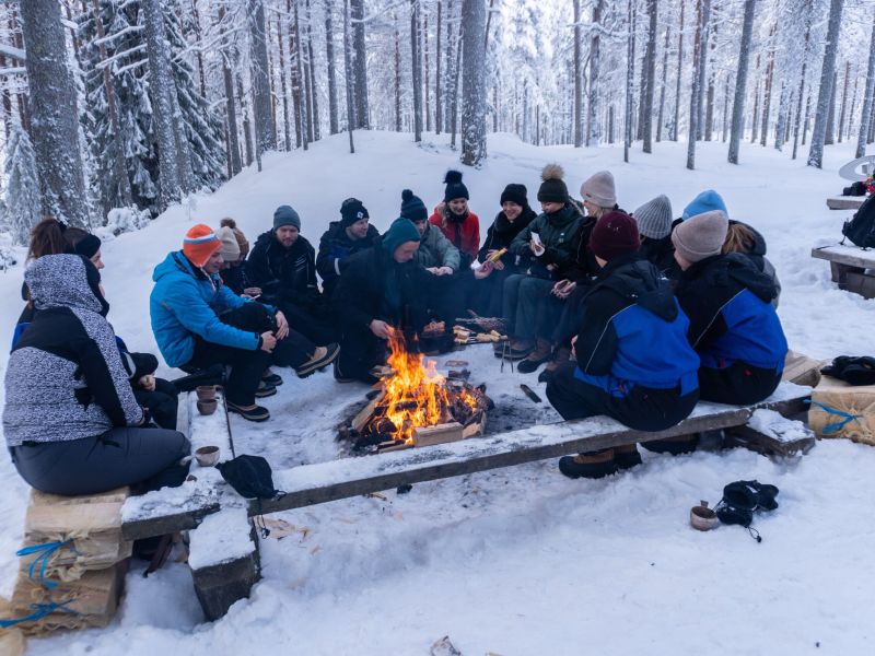 People having lunch around an open fire in winter.