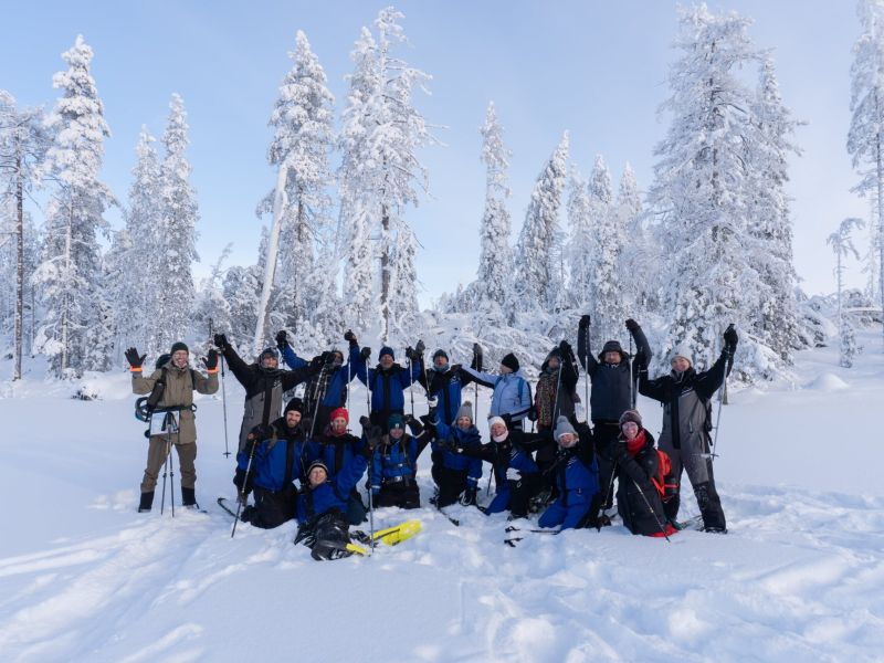 A group of people in the snowy scenery smiling and waving happily.