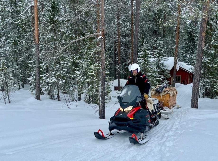 A man driving a snowmobile which is pulling a sledge with gear